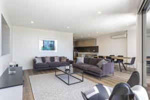 a living room with two couches and a table at Blairgowrie Apartment 1 - on the beach in Blairgowrie