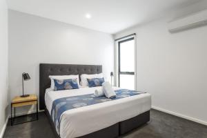 a white bedroom with a large bed with blue pillows at Blairgowrie Apartment 2 - on the beach in Blairgowrie
