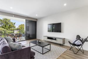 a living room with a couch and a tv at Blairgowrie Apartment 2 - on the beach in Blairgowrie