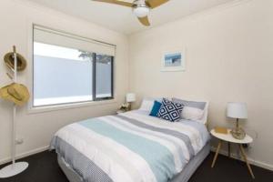 a white bedroom with a bed and a window at Windella Escape in Rosebud