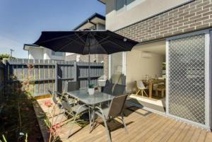 a patio with an umbrella and a table and chairs at Windella Escape in Rosebud