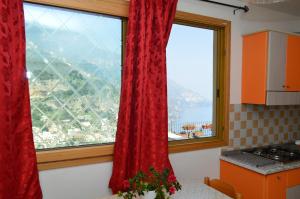 a kitchen with two large windows with red curtains at La Casarella Apartment Positano - Stunning View in Positano
