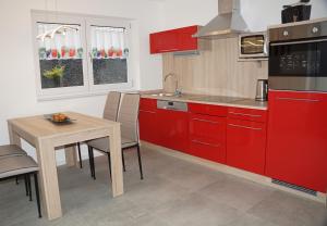een keuken met rode kasten en een houten tafel bij Apartment Seven in Ringsheim