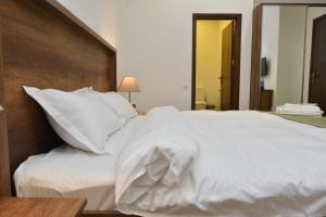 a large white bed with white sheets and pillows at Hotel King Tom in Tbilisi City