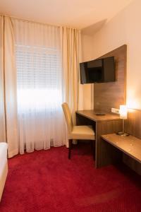 a hotel room with a desk and a television at Hotel Restaurant Jaegerhof in Kerpen