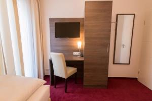 a room with a desk with a chair and a television at Hotel Restaurant Jaegerhof in Kerpen