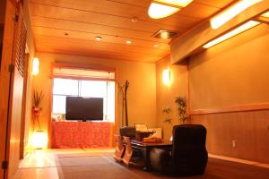 a room with a table and chairs and a television at Okinawa Minshuku Kariyushi in Shirahama