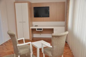 Habitación con mesa, 2 sillas y TV. en Hotel Prima, en Pristina