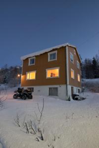 a house in the snow with a quad bike in front of it at Adventure Senja in Skrollsvika