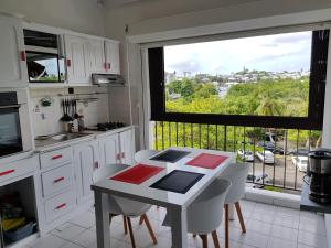 a kitchen with a table and chairs and a window at Joli T2 à 5 min de la plage in Le Gosier