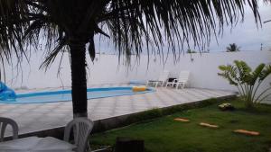 a swimming pool with two chairs and a palm tree at Casa Praia Lagoa dos Tambaquis - Abaís in Estância