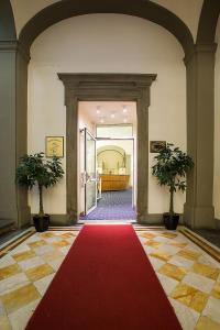 a red carpet in a hallway with two potted plants at Relais Hotel Centrale "Dimora Storica" in Florence