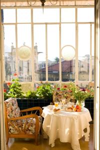 Villa Olimpo في رابالو: طاولة مع قماش الطاولة البيضاء والكراسي والنوافذ
