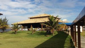 Ein Resort mit einem strohgedeckten Gebäude mit Palmen in der Unterkunft Maravilhosa Villa com Piscina in Arraial do Cabo