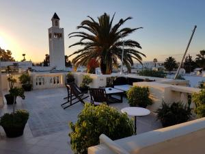 a rooftop patio with tables and a clock tower at Maison d'Hôtes Dar Ennassim in La Marsa
