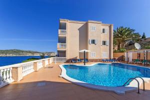 a swimming pool in front of a building at Apartamentos Amores San Telmo in Sant Elm