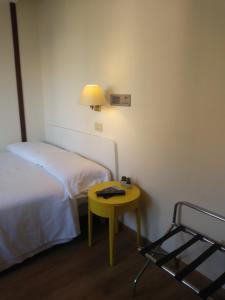Habitación pequeña con cama y mesa amarilla. en Hotel La Capannina, en Génova