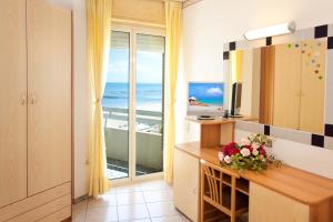 um quarto com uma secretária e vista para o oceano em Hotel Caesar em Cesenatico