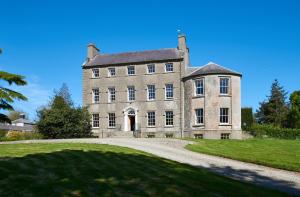 stary kamienny dom z podjazdem przed domem w obiekcie Ballydugan Country House w mieście Downpatrick