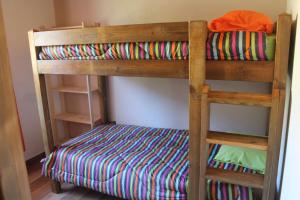 a wooden bunk bed with a colorful striped blanket at les cases prés du lac in Cilaos