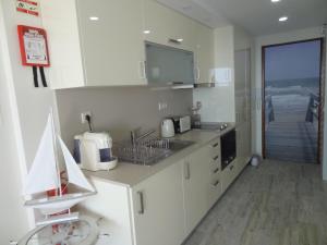 セジンブラにあるAkisol Sesimbra Beach IIIの白いキャビネット付きのキッチン、海の景色を望む