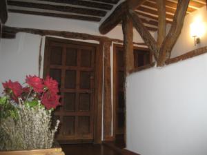 Casa Rural Margarita'S في Sotillo de la Ribera: غرفة مع باب و مزهرية مع الزهور الحمراء