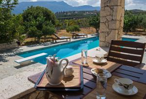 a wooden table with a tea set on it next to a pool at Panorama Villa Private Pool, BBQ, Parking in Sitia