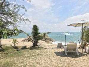 a beach with two chairs and an umbrella and the ocean at Paradise Lamai Bungalow in Lamai