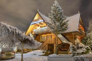 ザコパネにあるWilla Koisowkaの雪上のクリスマスツリーの丸太小屋