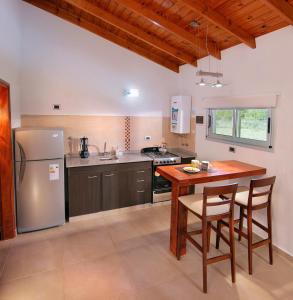 a kitchen with a wooden table and a refrigerator at Altos del Rio (Solo parejas) in Los Reartes