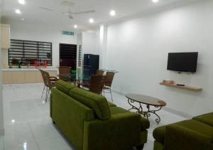 sala de estar con sofá verde y mesa en Penginapan The CityScape - Cukup Rehat & Tidur Lena Hingga Pagi, en Lumut