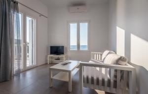 een witte woonkamer met een stoel en een tafel bij Milos Waves Luxury Apartments in Pollonia