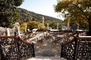 a patio with tables and chairs and a fence at Archontiko Stathopoulou in Agios Georgios Nilias