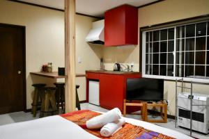 a room with a bed and a kitchen with red cabinets at Altitude Madarao in Iiyama