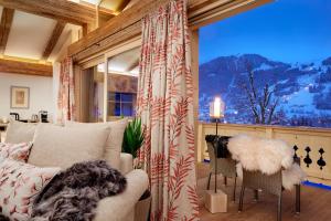 a living room with a couch and a large window at Tennerhof Luxury Chalets in Kitzbühel