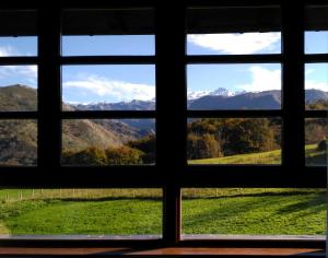 una ventana con vistas a un campo y a las montañas en La Casona de Torió en Torío