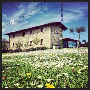 a stone building on a hill with a field of flowers at Hotel Artetxe in Bilbao