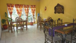a dining room with tables and chairs and windows at Hostal Doña Marta in San Salvador