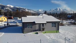 a house in the snow with mountains in the background at Apartmán Pod Klinom in Pribylina