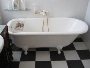 a white bath tub in a bathroom with a checkered floor at Ladismith Manor in Ladismith