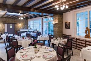 une salle à manger avec des tables blanches, des chaises et des fenêtres dans l'établissement Grand Hotel Pelisson, à Nontron