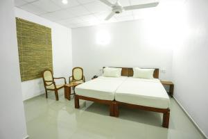 biały pokój z łóżkiem i 2 krzesłami w obiekcie Candila Hotel & Sports Club w mieście Habarana