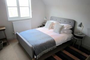 Un dormitorio con una cama grande con almohadas. en Crown Cottage - Prime Orford Location en Orford