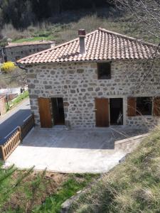 una pequeña casa de piedra con puertas de madera y una carretera en Gîte-La Combelle, en Dornas