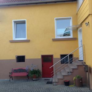 a yellow house with a red door and a bench at Feriendomizil strasser in Homburg