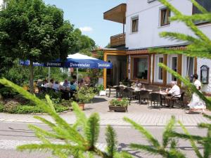een groep mensen die aan tafels buiten een gebouw zitten bij Cafe Rundblick in Baiersbronn