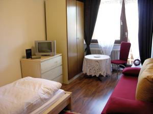 1 dormitorio con 1 cama, TV y mesa en Cafe Rundblick, en Baiersbronn