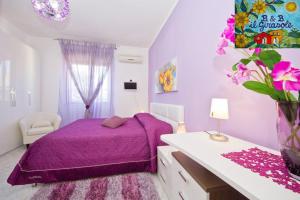 - une chambre violette avec un lit et un vase de fleurs dans l'établissement Bed and Breakfast Il Girasole, à Mondello