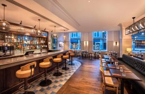 um restaurante com um bar e mesas e cadeiras em Leonardo Hotel Cardiff em Cardiff
