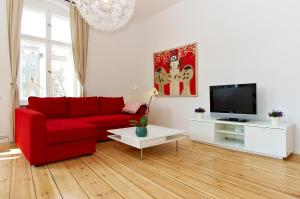 een woonkamer met een rode bank en een tv bij Apartment Prenzlauer Allee in Berlijn